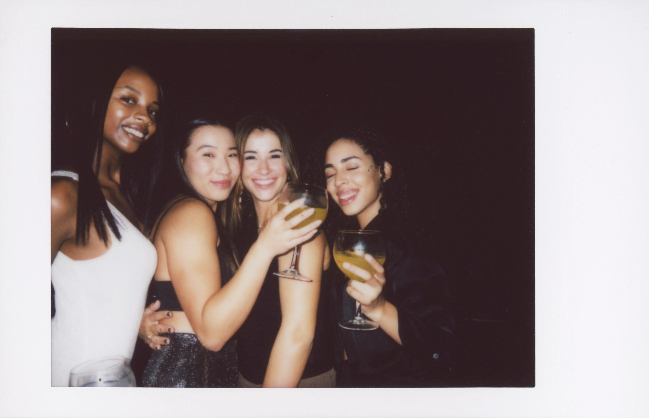 Four friends posing with cocktails during a night out