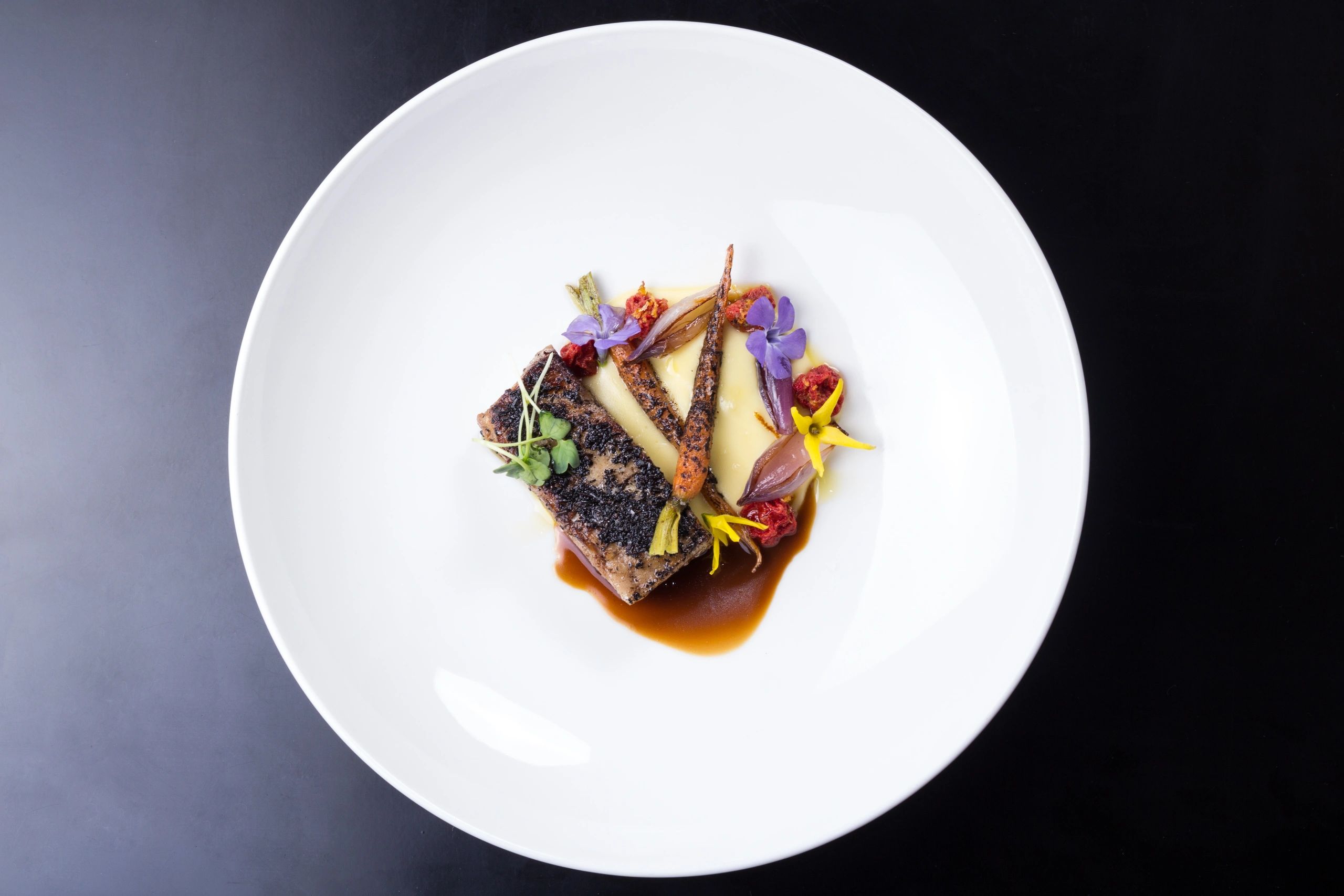 Plated ribs with garnish on a dark plate