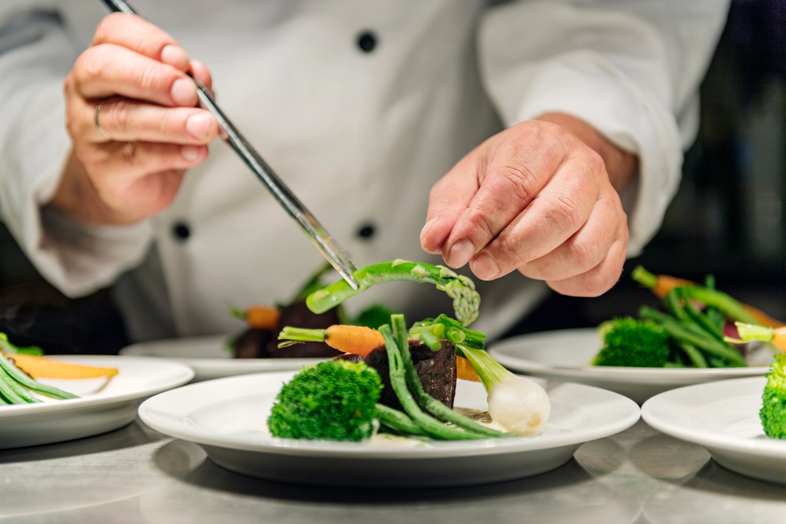 Chef finishing a plated dish in a restaurant kitchen